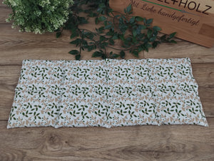 weißes Körnerkissen in der Größe 50*20cm mit grünen Blättern und beigefarbenen Zweigen