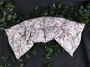 Unser Körnerkissen Kirschblüte ist im Bogen hingelegt. Es zeigt eine Vielzahl an aufgehenden Kirschblüten. Der Hintergrund ist in einem dezenten hellgrau gehalten. Darauf abgebildet sind Äste des Kirschbaums, der im Anfang seiner Blüte steht. Viele der Triebe sind schon geöffnet und zeigen die Schönheit der Kirschblüte. Die Blütenblätter sind weiß bis hellrosa, wo hingegen der Blütenstempel in schwarz und einem dunklem Beerenton gehalten ist.