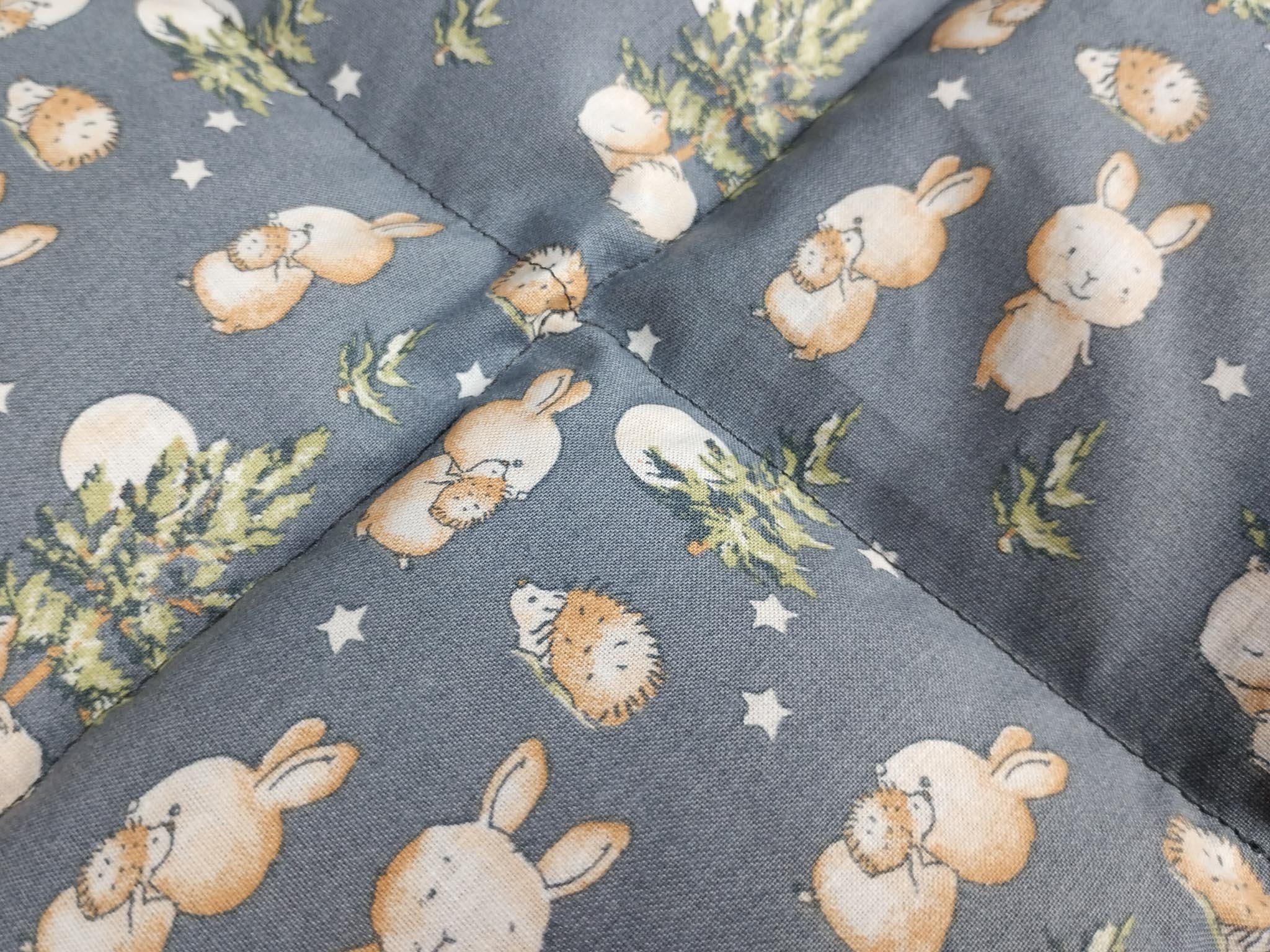 Körnerkissen mit dunkelgrauem Hintergrund auf dem viele Igel, Hasen und Füchse zu sehen sind