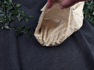 personalisiertes Körnerkissen mit dem Namen Angelina. Das Hauptmotiv in beige mit weißen Ranken und der Name weiß gestickt auf beigem Stoff.