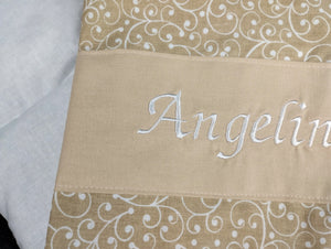 personalisiertes Körnerkissen mit dem Namen Angelina. Das Hauptmotiv in beige mit weißen Ranken und der Name weiß gestickt auf beigem Stoff.