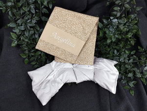 personalisiertes Körnerkissen mit dem Namen Angelina. Das Hauptmotiv in beige mit weißen Ranken und der Name weiß gestickt auf beigem Stoff.