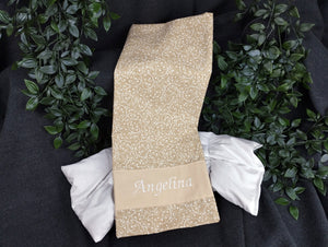 personalisiertes Körnerkissen mit dem Namen Angelina. Das Hauptmotiv in beige mit weißen Ranken und der Name weiß gestickt auf beigem Stoff.