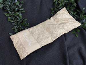 personalisiertes Körnerkissen mit dem Namen Angelina. Das Hauptmotiv in beige mit weißen Ranken und der Name weiß gestickt auf beigem Stoff.