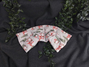 Körnerkissen im weihnachtlichem Look mit Weihnachtsgnomen, die eine Laterne tragen. Verziert wird die graue Landschaft mit grünen Tannenbäumen