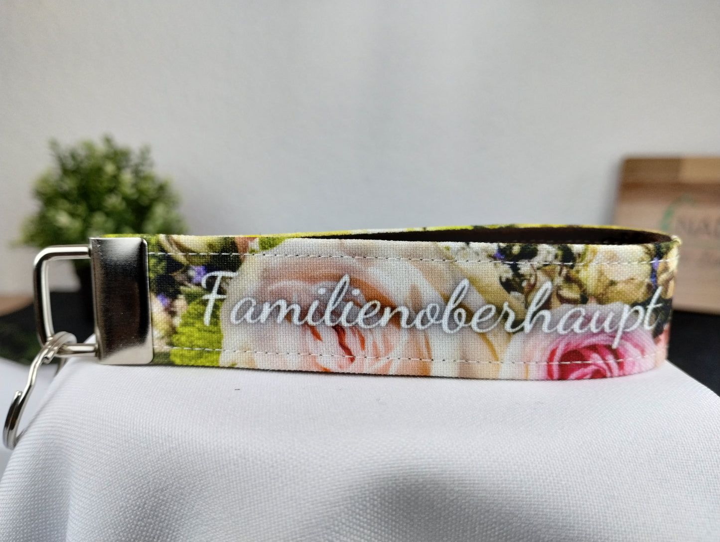 Personalisierbarer Schlüsselanhänger mit buntem Blumenmotiv, weißer Schrift und innen mit braunem Filz