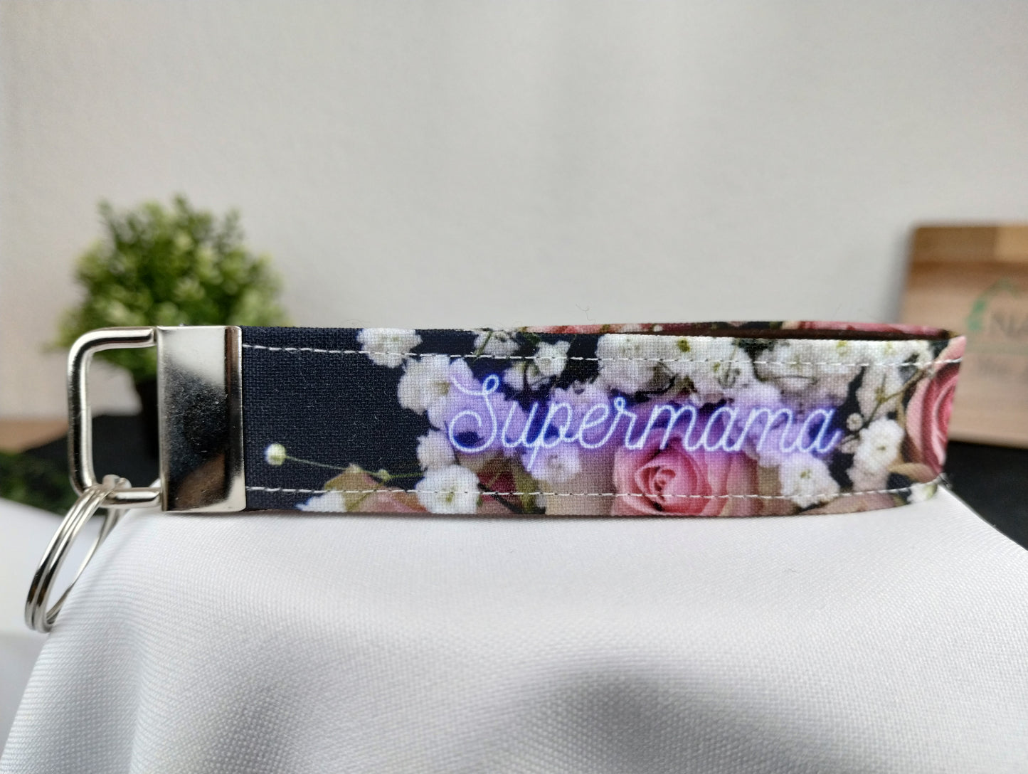 Personalisierbarer Schlüsselanhänger mit dunklem Blumenmotiv, lila/weißer Schrift und innen mit braunem Filz