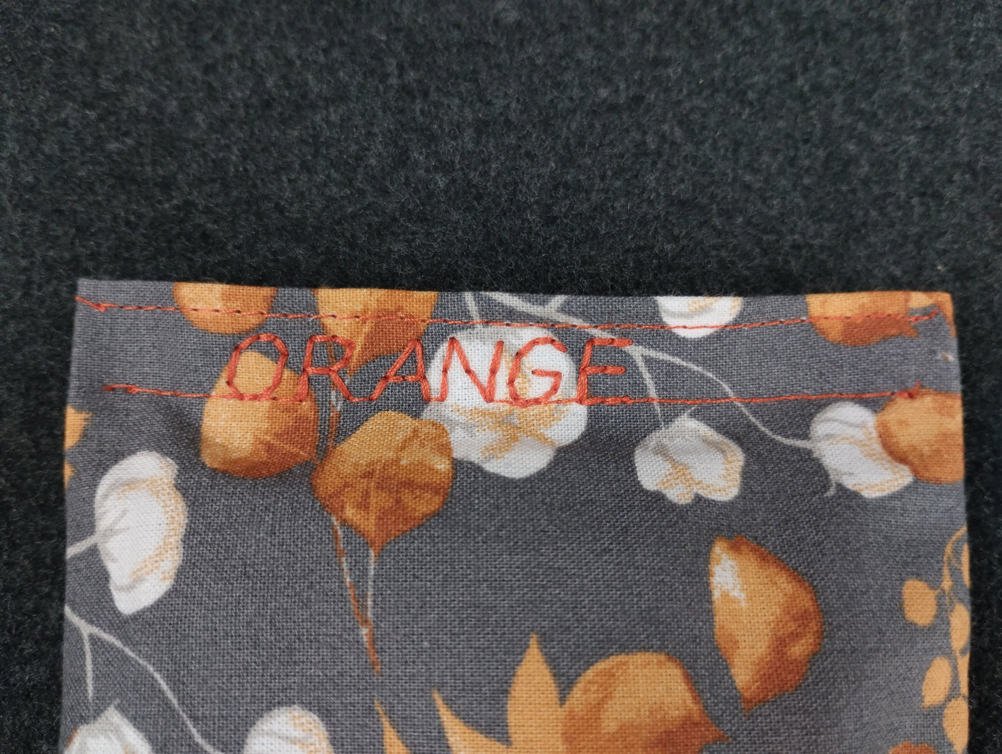 fertiges Duftkissen mit Eucalyptus/Baumwollmotiv in grau/orange. Personalisiert mit dem Wort orange in einem orangefarbenem Nähgarn