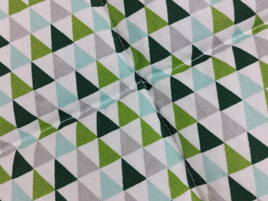 Körnerkissen mit weißem Hintergrund, worauf viele Dreiecke in grau, grün und türkis abgebildet sind