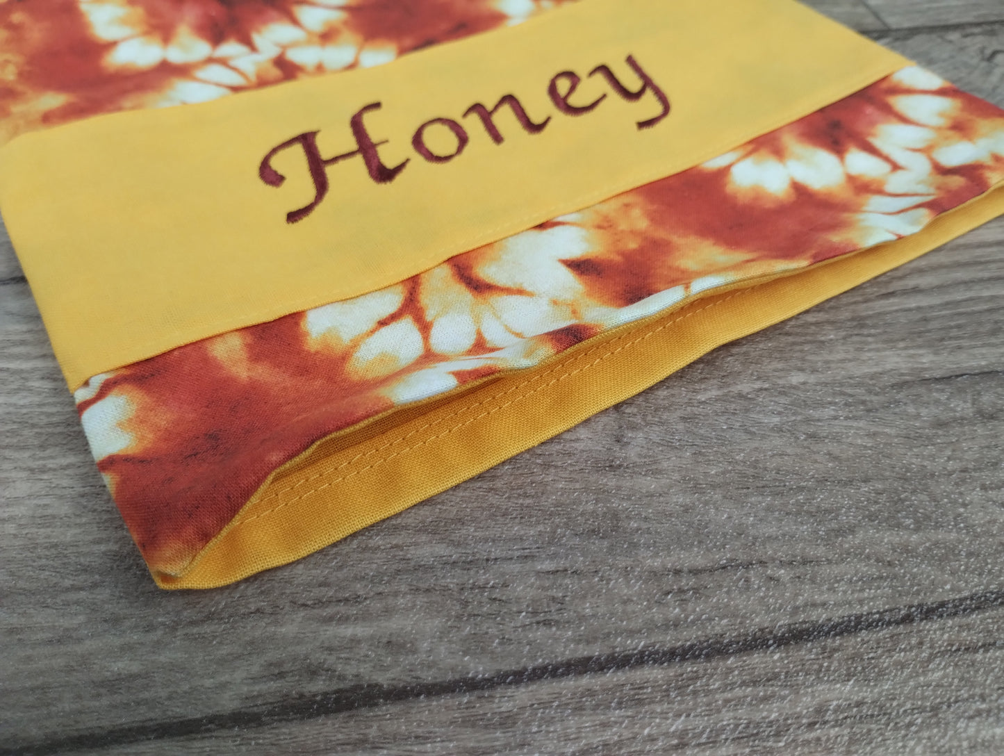 personalisiertes Körnerkissen in gelb rot mit der gestickten Personalisierung Honey.