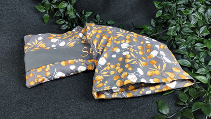 personalisiertes Körnerkissen mit Bezug aus unserem Eucalyptus/Baumwollmotivstoff in grau/orange. Personalisierung auf dunkelgrauem Stoff mit hellorangener Schrift