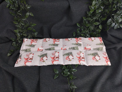 Körnerkissen im weihnachtlichem Look mit Weihnachtsgnomen, die eine Laterne tragen. Verziert wird die graue Landschaft mit grünen Tannenbäumen